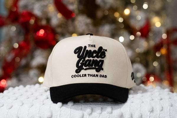 Beige cap with black text 'The Uncle Gang Cooler Than Dad' on a blurred festive background