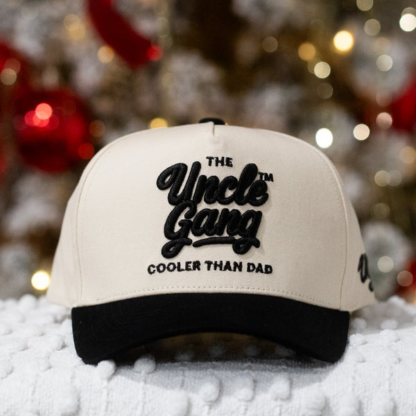 Beige cap with black text 'The Uncle Gang Cooler Than Dad' on a blurred festive background