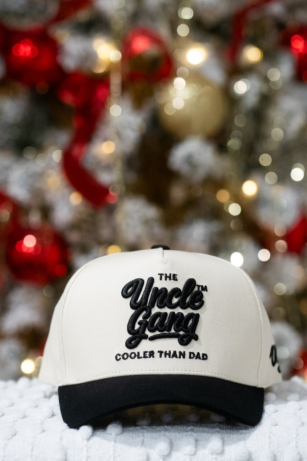 White cap with 'The Uncle Gang Cooler Than Dad' text in front of a decorated Christmas tree.