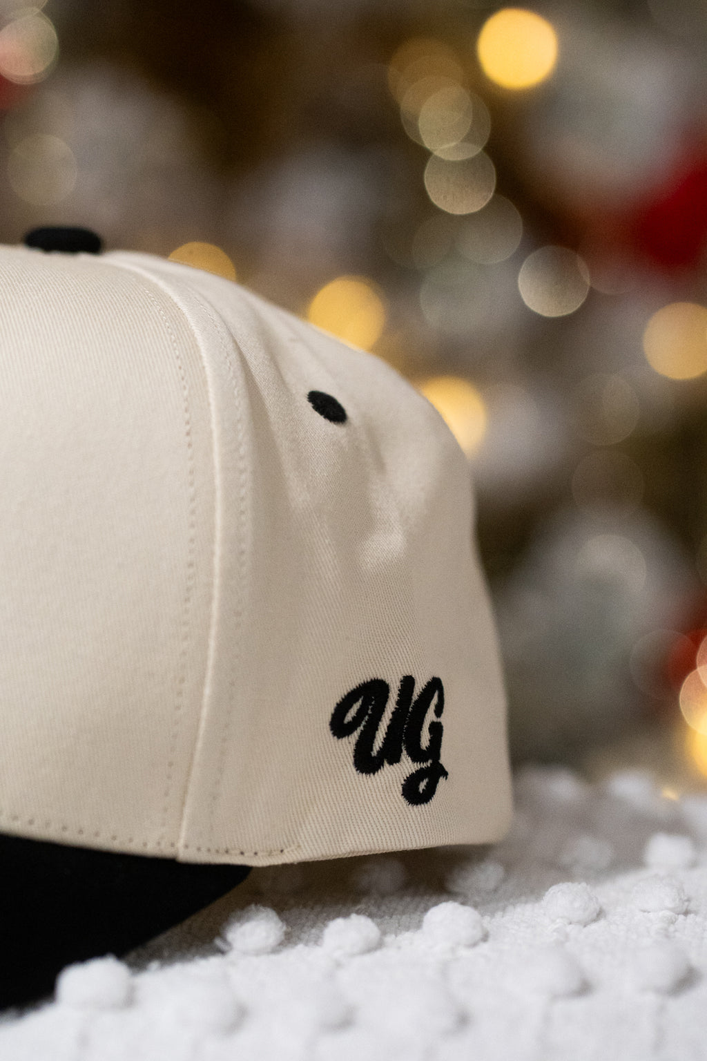 Beige cap with 'UG' logo on a blurred background