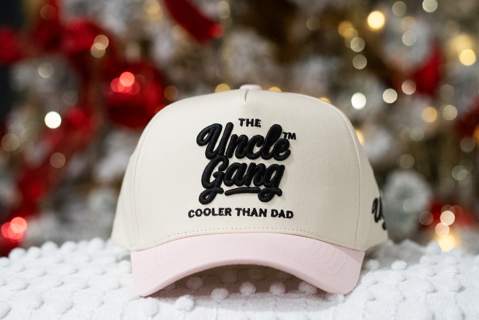 Beige and pink cap with 'The Uncle Gang Cooler Than Dad' text on a snowy background