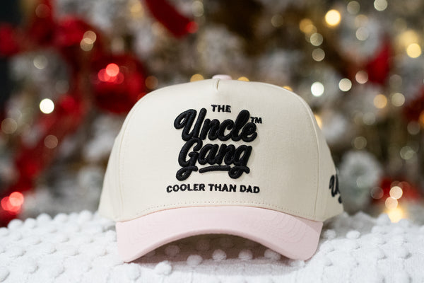Beige and pink cap with 'The Uncle Gang Cooler Than Dad' text on a snowy background
