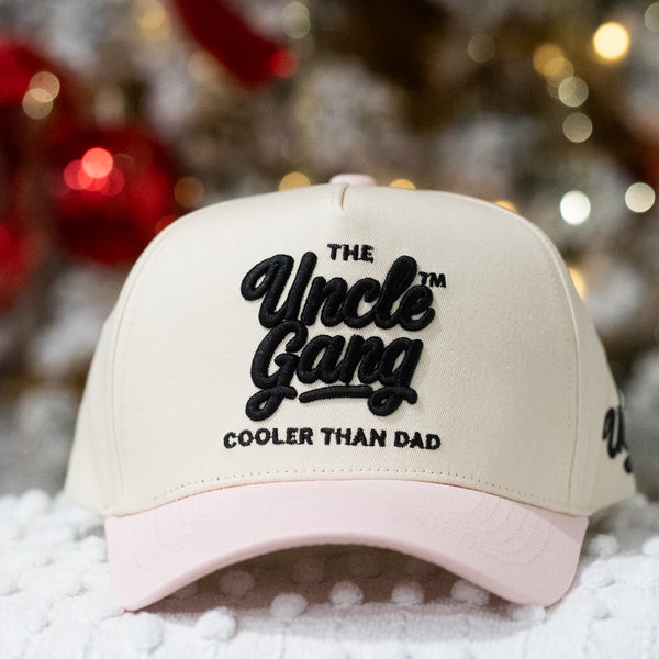 Beige and pink cap with 'The Uncle Gang Cooler Than Dad' text on a snowy background