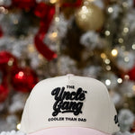 Beige cap with 'The Uncle Gang Cooler Than Dad' text in front of a decorated Christmas tree.