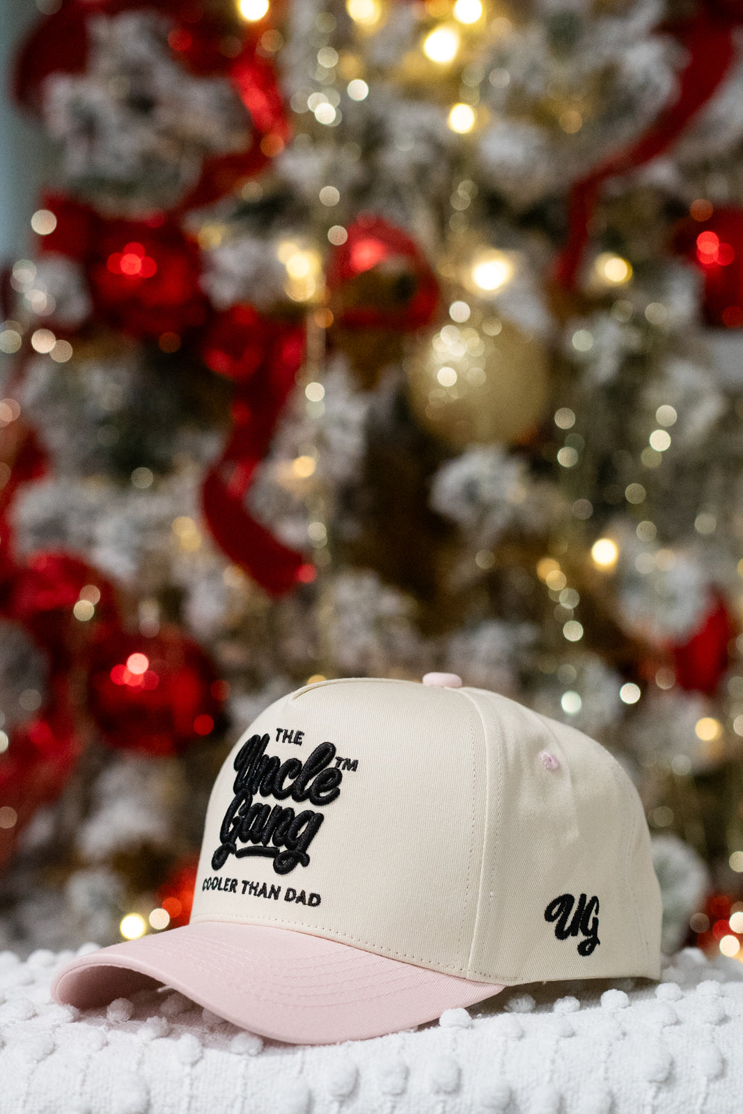 Beige cap with text in front of a decorated Christmas tree