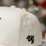 Beige and pink cap with 'UG' logo on a blurred background