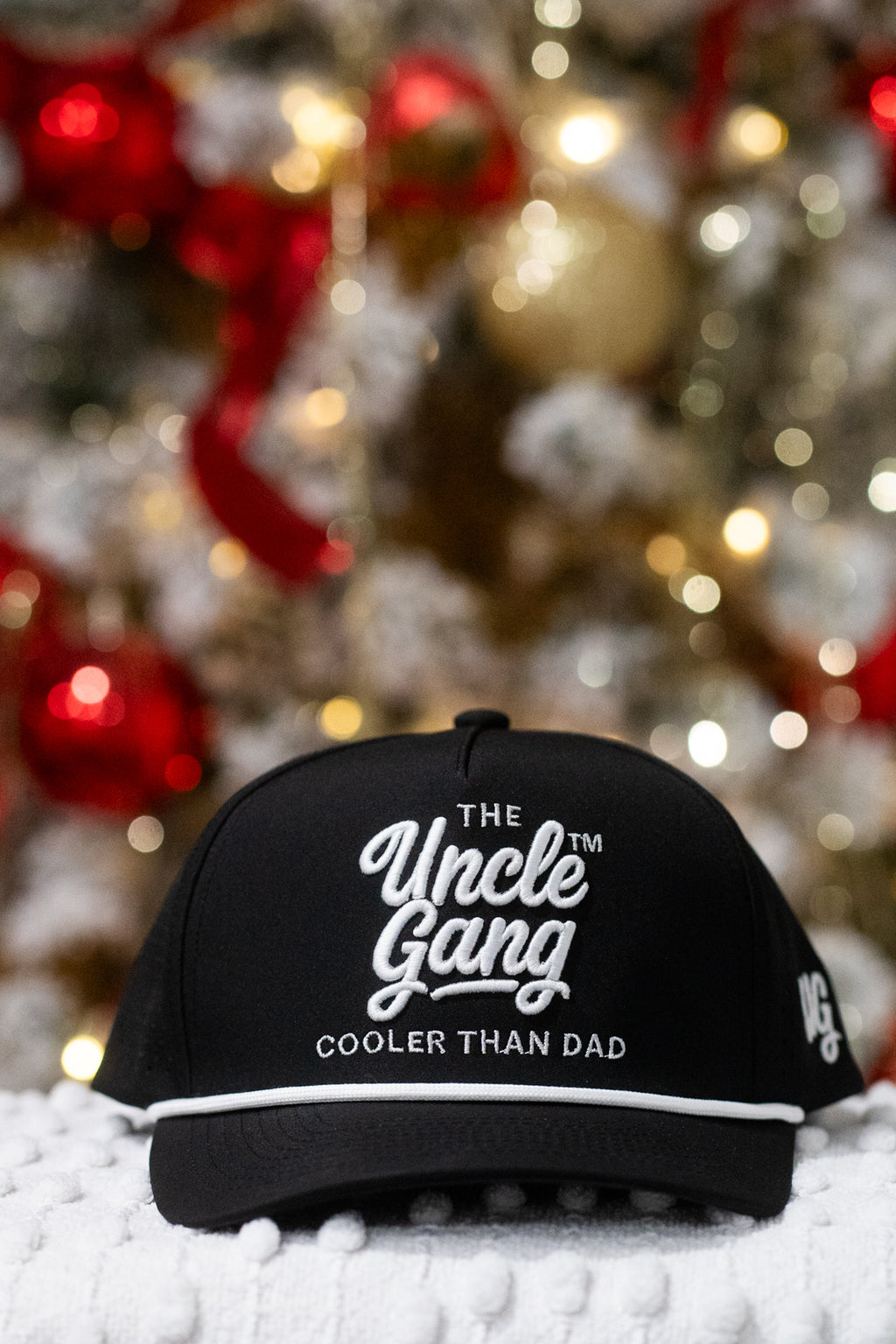Black cap with 'The Uncle Gang Cooler Than Dad' text in front of a decorated Christmas tree.