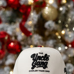 Cap with 'The Uncle Gang Cooler Than Dad' text in front of a decorated Christmas tree.