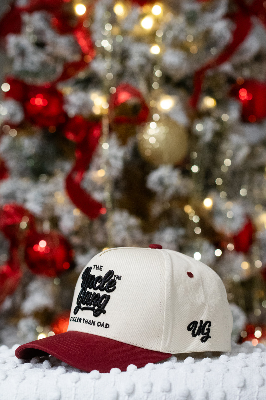 White and red cap with text in front of a decorated Christmas tree