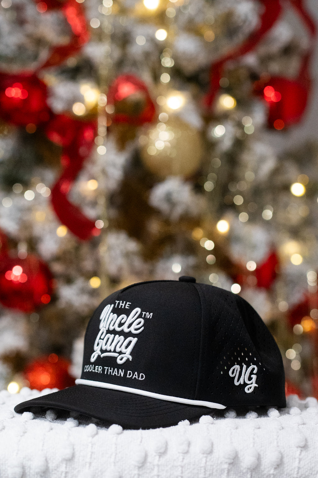 Black cap with text in front of a decorated Christmas tree