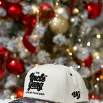 White cap with 'The Uncle Gang' logo in front of a decorated Christmas tree.
