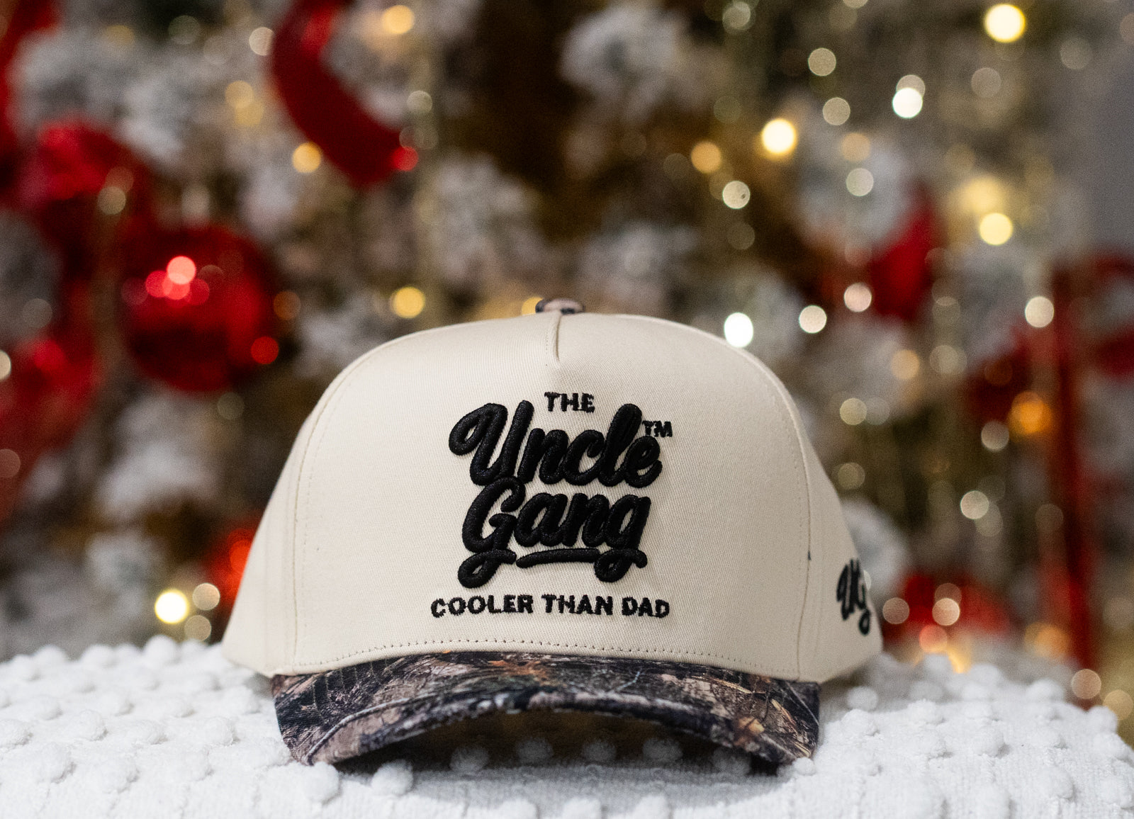 Beige cap with 'The Uncle Gang Cooler Than Dad' text in front of a Christmas tree.