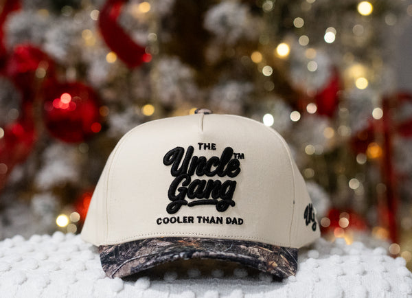 Beige cap with 'The Uncle Gang Cooler Than Dad' text in front of a Christmas tree.