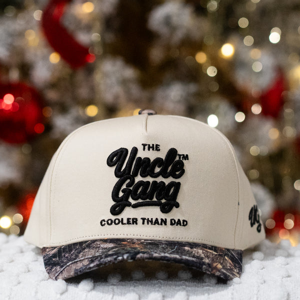 Beige cap with 'The Uncle Gang Cooler Than Dad' text in front of a Christmas tree.