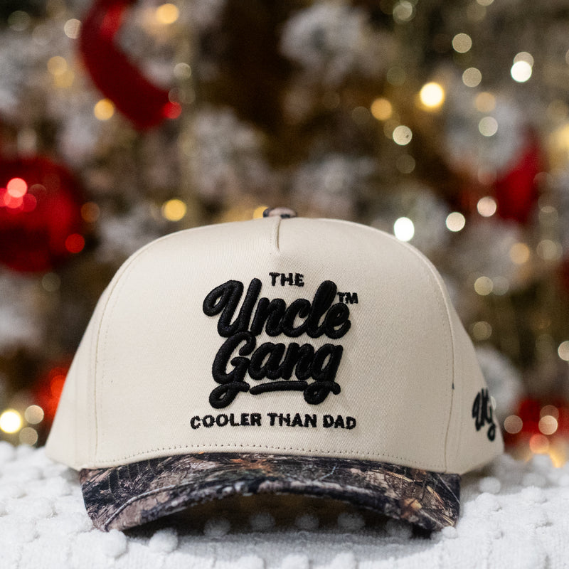 Beige cap with 'The Uncle Gang Cooler Than Dad' text in front of a Christmas tree.