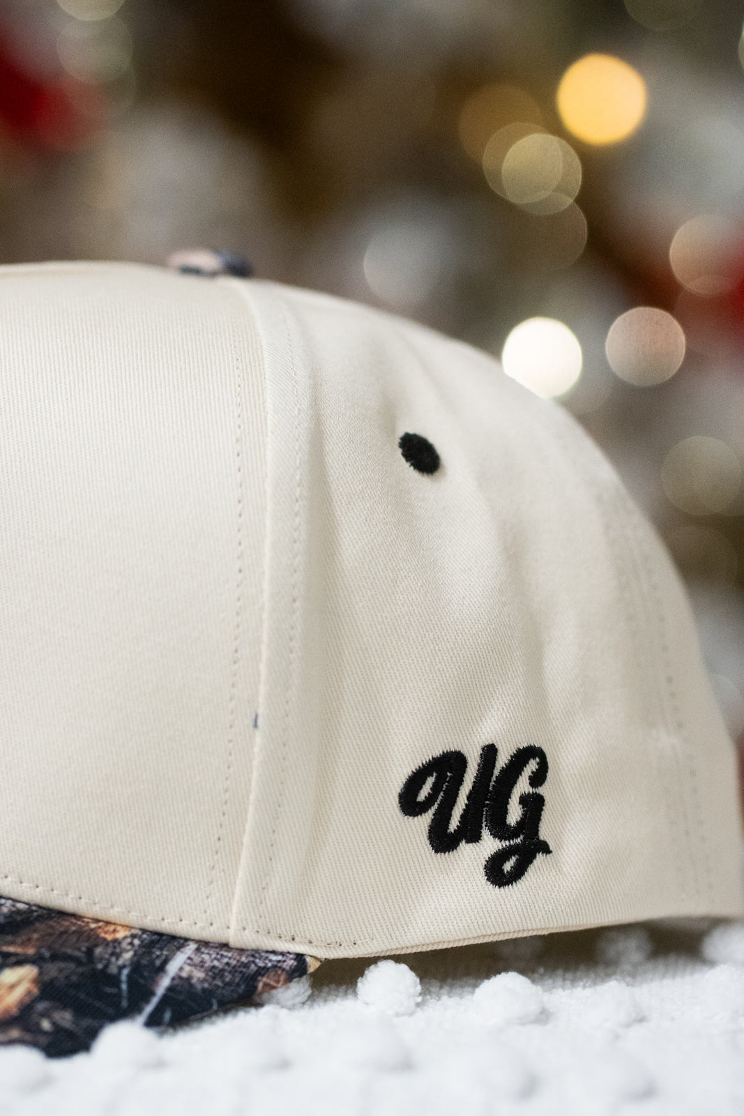 Beige cap with 'UG' logo on a blurred background