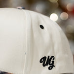 Beige cap with 'UG' logo on a blurred background